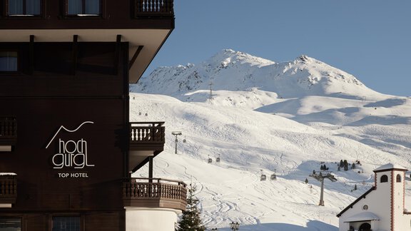 A hotel with a view of snow-covered mountains. In the foreground, you can see charming architecture and the idyllic winter landscape. - TOP Hotel Hochgurgl - Hochgurgl