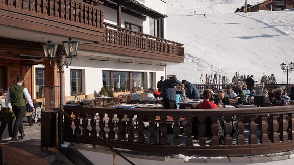 Eine Terrasse eines Bergrestaurants mit vielen Gästen, die die Aussicht genießen. Im Hintergrund sind schneebedeckte Berge zu sehen. - TOP Hotel Hochgurgl - Hochgurgl
