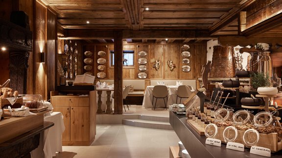Ein gemütliches Restaurant mit Holzdekor und warmem Licht. Die Tische sind stilvoll gedeckt, und ein Buffet mit verschiedenen Speisen ist zu sehen. - TOP Hotel Hochgurgl - Hochgurgl