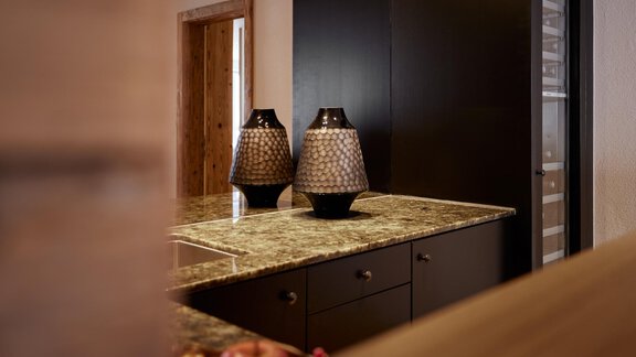 Eine moderne Küche mit einer eleganten Marmortheke und zwei dekorativen Vasen. Die Wände sind in dunklen Tönen gehalten, was eine stilvolle Atmosphäre schafft. - TOP Hotel Hochgurgl - Hochgurgl