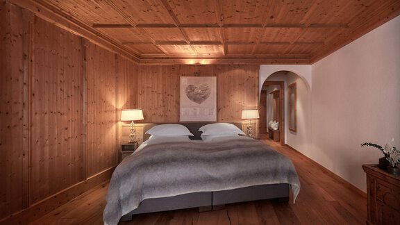 Ein gemütliches Schlafzimmer mit Holzverkleidung und einem großen Doppelbett. Sanfte Beleuchtung und stilvolle Dekoration schaffen eine warme Atmosphäre. - TOP Hotel Hochgurgl - Hochgurgl