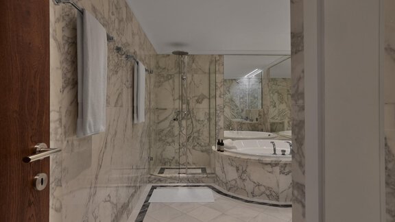 Ein luxuriöses Badezimmer mit marmornen Wänden und glänzenden Armaturen. Eine Dusche und ein freistehendes Bad ergänzen die elegante Ausstattung. - TOP Hotel Hochgurgl - Hochgurgl