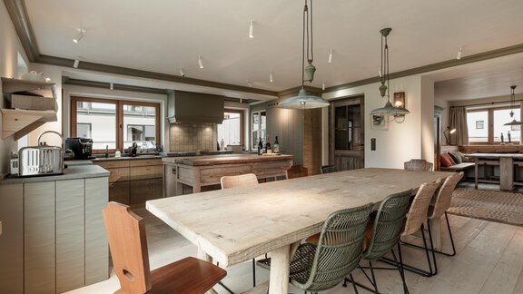 A modern kitchen with a large wooden table and stylish chairs. The bright room lighting creates an inviting atmosphere. - Chalet Cecilia by MYALPS - Obergurgl 