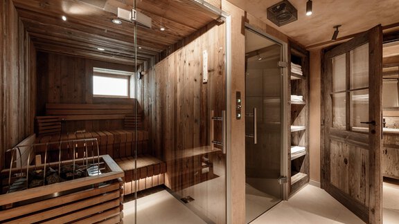 A luxurious wellness area with a modern sauna made of light wood and a glass shower room. The warm wood tones create a relaxing atmosphere. - Chalet Cecilia by MYALPS - Obergurgl 