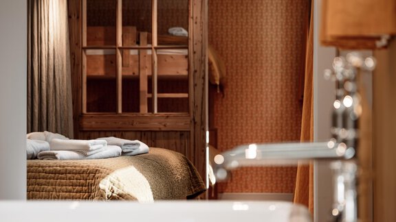 A cozy room with a double bed and a bunk bed in the background. In the foreground, a modern sink is visible. - Chalet Cecilia by MYALPS - Obergurgl 