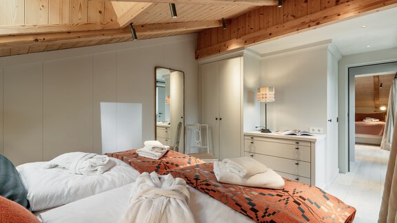 An elegant bedroom with two beds and a wooden ceiling. There is a large mirror and bright light that makes the room cozy. - Chalet Cecilia by MYALPS - Obergurgl 
