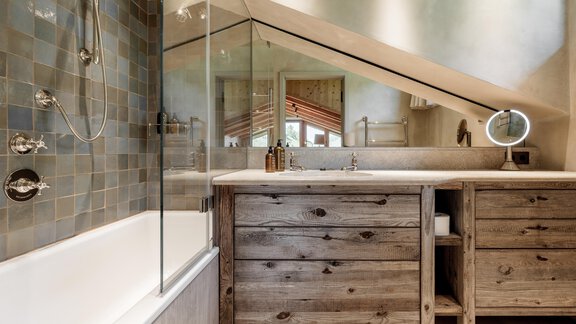 A modern bathroom with a freestanding bathtub and an elegant shower. The furniture is made of light wood and harmonizes with the green tiles. - Chalet Cecilia by MYALPS - Obergurgl 