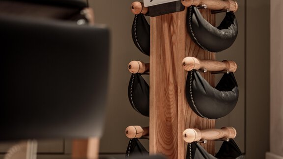 A wooden stand with black training equipment is in a bright room. An exercise instruction hangs at the front. - Chalet Cecilia by MYALPS - Obergurgl 