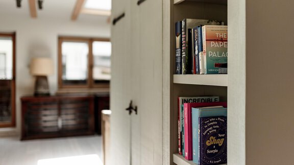 A cozy room with a bookshelf and a lamp. The books are clearly visible and give the room an inviting atmosphere. - Chalet Cecilia by MYALPS - Obergurgl 