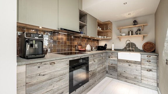 A modern kitchen with wooden cabinets and an elegant gray layout. The space is well-lit and offers a practical design. - Chalet Cecilia by MYALPS - Obergurgl 