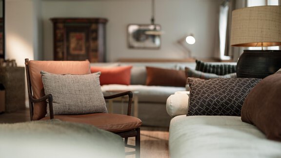 A stylishly furnished living room with comfortable sofas and a wooden chair. The colors and textures create a cozy atmosphere. - Chalet Cecilia by MYALPS - Obergurgl 