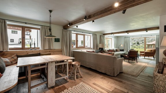 A cozy living space with wooden furniture and large windows. The room is bright and inviting, with an open connection to the nature outside. - Chalet Cecilia by MYALPS - Obergurgl 