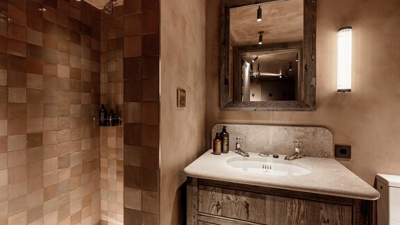 A modern bathroom with a shower and a wooden sink. The walls are designed in warm tones and the lighting is soft. - Chalet Cecilia by MYALPS - Obergurgl 