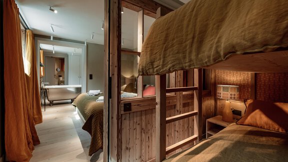A modern room with a bunk bed and a cozy sleeping area. The warm colors and wooden details create an inviting atmosphere. - Chalet Cecilia by MYALPS - Obergurgl 