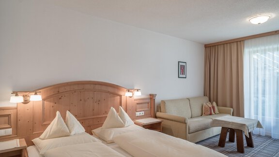 A cozy room with two single beds and a sofa. Large windows provide plenty of daylight. - Ferienwohnung de Luxe Alpenresidenz am Mühlbach - Obergurgl 