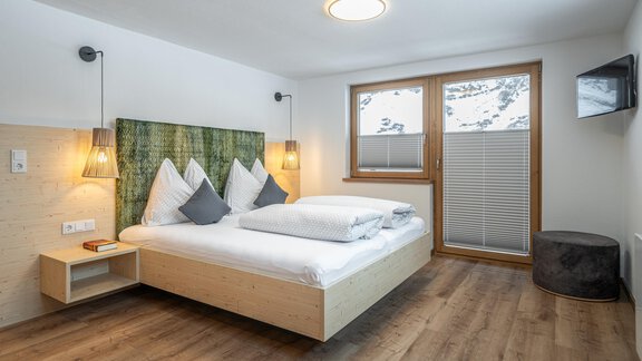 A modern bedroom with a double bed and a cozy atmosphere. Large windows let in plenty of light and offer a view outside. - Haus Gstrein - Obergurgl 