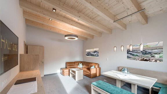 Ein modern eingerichteter Wohnraum mit Holzdecken und eleganten Möbeln. Große Fenster und Kunstwerke verleihen dem Raum eine einladende Atmosphäre. - Skihotel Haus Gurgl - Obergurgl 