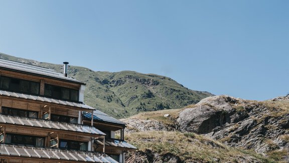 A modern building in the mountains with a wooden façade. The sky is clear and blue. - The Crystal VAYA Unique - Obergurgl 