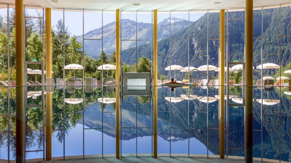 An elegant indoor pool with large windows showcasing a stunning mountain landscape. The pool reflects the surroundings and invites relaxation. - Vivea 4* Hotel Umhausen im Ötztal - Umhausen
