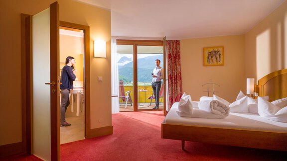 A cozy hotel room with a view of the mountains. Two people are standing in different areas of the room. - Vivea 4* Hotel Umhausen im Ötztal - Umhausen