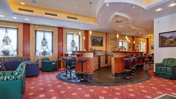 A cozy bar with colorful chairs and sofas in a modern ambiance. Large windows let in plenty of daylight. - Hotel Vent - Vent