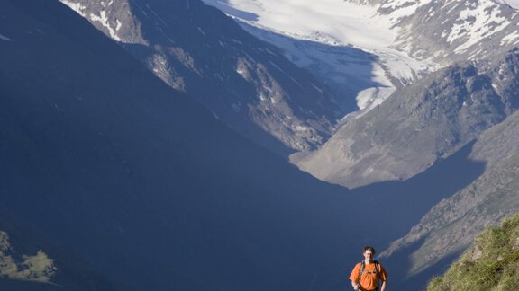 Two hikers on a mountain path with snow-covered peaks in the background. The landscape is green and the mountains are majestic. - Hotel Vent - Vent