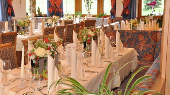 Ein elegantes Restaurant mit festlich gedeckten Tischen. Blumenarrangements und dekorative Servietten schaffen eine einladende Atmosphäre. - Hotel Tauferberg - Niederthai