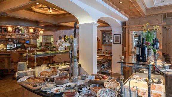 Ein einladendes Buffet mit einer Vielzahl von Speisen, darunter Brot, Obst und Aufschnitt. Der Essbereich ist liebevoll dekoriert mit Blumen und Holzdetails. - Hotel Tauferberg - Niederthai