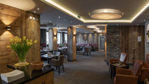 Ein elegantes Restaurant mit rustikalem Holzdekor und gemütlichen Sitzbereichen. Der Raum ist hell erleuchtet und lädt zum Verweilen ein. - Hotel Tauferberg - Niederthai