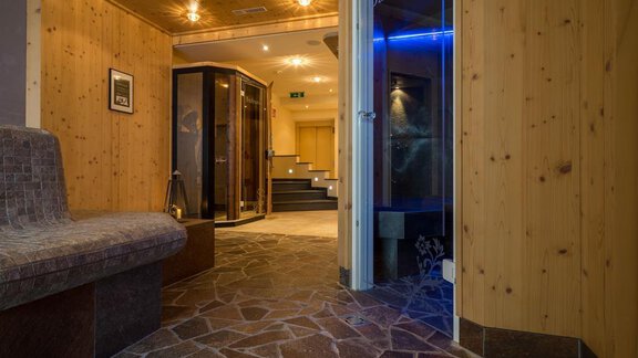 Ein einladender Eingangsbereich mit Holzverkleidung und einem gepflasterten Boden. Sicht auf eine Sauna und Treppen, die in einen weiteren Raum führen. - Hotel Tauferberg - Niederthai