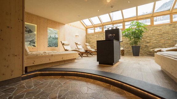 Ein entspannender Wellnessbereich mit Holzverkleidungen und großen Fenstern. Die angenehme Atmosphäre wird durch Pflanzen und gemütliche Liegen ergänzt. - Hotel Tauferberg - Niederthai