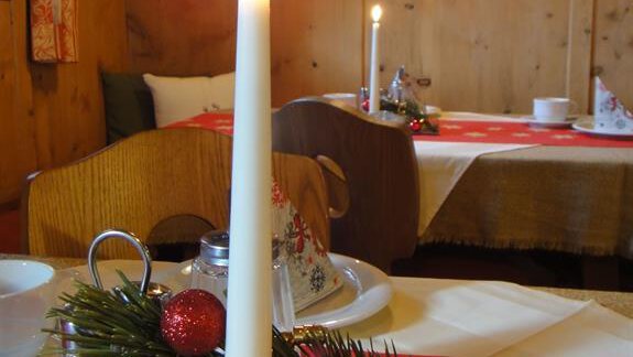 A cozy restaurant with festively set tables. On one table, there is a candle in a glass and Christmas decorations. - Haus Elisabeth - Vent