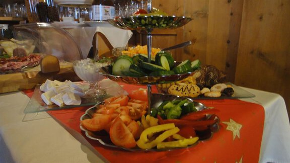 A selection of fresh vegetables on a multi-tiered serving platter. Underneath are tomatoes, cucumbers, and bell peppers, surrounded by various side dishes. - Haus Elisabeth - Vent