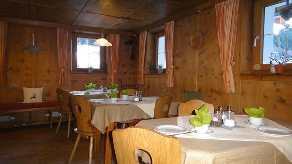 A cozy restaurant with wooden walls and rustic furniture. The tables are neatly set and decorated with fresh plants. - Haus Elisabeth - Vent
