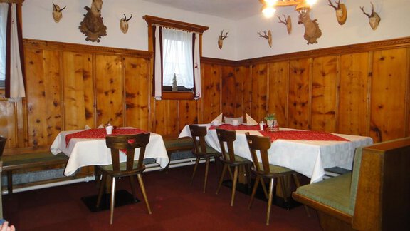 A cozy restaurant with wooden walls and rustic tables. The decorative antler heads on the walls give the space a traditional character. - Haus Elisabeth - Vent