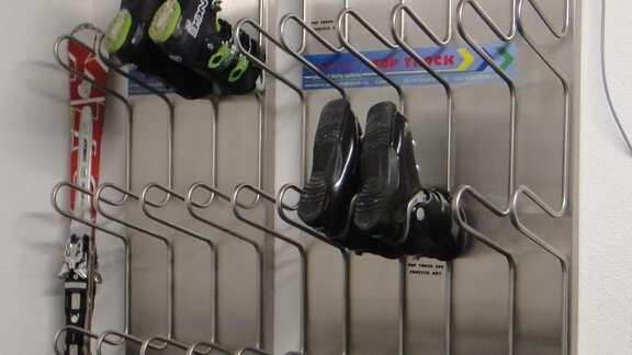 A steel rack with multiple holders for ski boots and skis. The boots are neatly arranged on the rack. - Haus Elisabeth - Vent