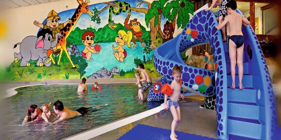 A child-friendly indoor pool with a slide and cheerful pictures on the wall. Children are splashing in the water and enjoying the activities. - Erlebnishallenbad Freizeit Arena - Sölden