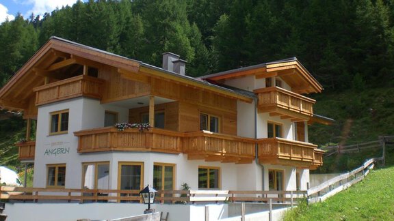 Ein modernes Chalet im Alpenstil mit Holzbalkonen und hellen Wänden. Umgeben von grünen Bergen und blauem Himmel. - Pension Angern - Obergurgl 