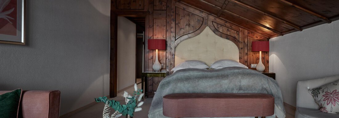 Junior Suite Mountain View | © TOP Hotel Hochgurgl (CC C) Ein gemütliches Schlafzimmer mit Holzwänden und einem stilvollen Bett. Das Zimmer ist elegant eingerichtet mit sanften Farben und verfügt über weiche Beleuchtung. - TOP Hotel Hochgurgl - Hochgurgl