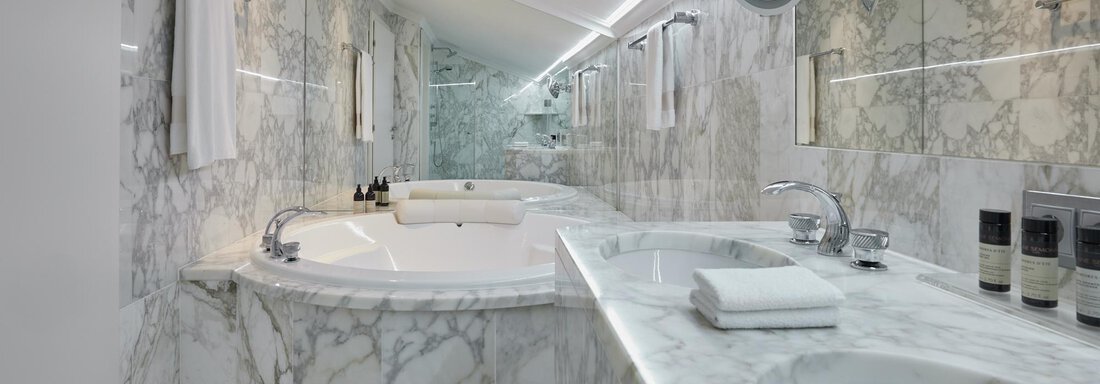 Ein elegantes Badezimmer mit marmorierten Wänden und modernen Armaturen. Es verfügt über eine Badewanne und einen Doppelwaschtisch. - TOP Hotel Hochgurgl - Hochgurgl