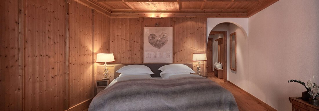 Ein gemütliches Schlafzimmer mit Holzvertäfelungen und einem großen Doppelbett. Sanftes Licht von zwei Nachttischlampen schafft eine einladende Atmosphäre. - TOP Hotel Hochgurgl - Hochgurgl