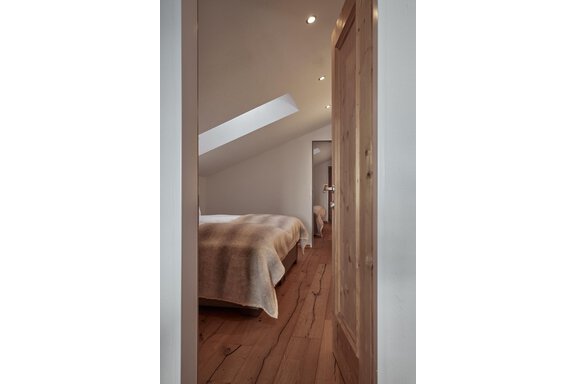 Ein gemütliches Schlafzimmer mit einem Bett und Holzboden. Der Raum hat ein modernes Design und viel Licht durch das Dachfenster. - TOP Hotel Hochgurgl - Hochgurgl