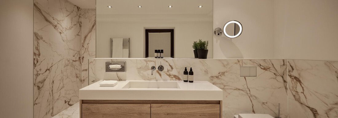 Ein modernes Badezimmer mit marmorierten Wänden und einem stilvollen Waschbecken. Gut ausgeleuchtet, mit minimalistischen Möbeln und einer kleinen Pflanze. - TOP Hotel Hochgurgl - Hochgurgl