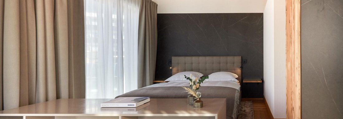 Panorama Suite Mountain View | © TOP Hotel Hochgurgl (CC C) Ein modernes Schlafzimmer mit einem gemütlichen Bett und großen Fenstern. Die Holzdecke und die hellen Vorhänge sorgen für eine helle und freundliche Atmosphäre. - TOP Hotel Hochgurgl - Hochgurgl