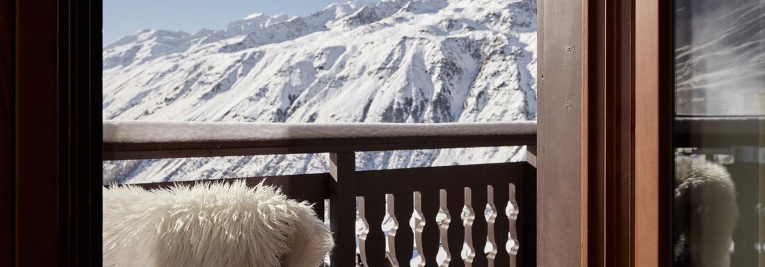 Ein schöner Balkon mit einem gemütlichen Stuhl und einer Aussicht auf schneebedeckte Berge. Der klare Himmel strahlt eine ruhige Winteratmosphäre aus. - TOP Hotel Hochgurgl - Hochgurgl