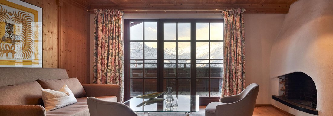 Heritage Suite Mountain View | © TOP Hotel Hochgurgl (CC C) Ein gemütliches Wohnzimmer mit Holzverkleidung und großen Fenstern, die einen Blick auf die Berge bieten. Zwei bequeme Sessel und ein Sofa laden zum Entspannen ein. - TOP Hotel Hochgurgl - Hochgurgl
