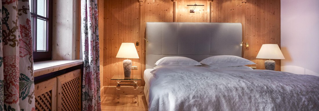 Ein gemütliches Schlafzimmer mit Holzvertäfelung und sanfter Beleuchtung. Das Bett ist einladend mit einem weichen Überwurf und dazu passen zwei Nachttische mit Lampen. - TOP Hotel Hochgurgl - Hochgurgl