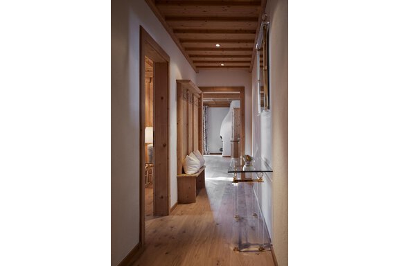 Ein gemütlicher Flur mit Holzverkleidung und hellen Wänden. Auf der linken Seite befindet sich eine Bank und ein Glas Tisch. - TOP Hotel Hochgurgl - Hochgurgl