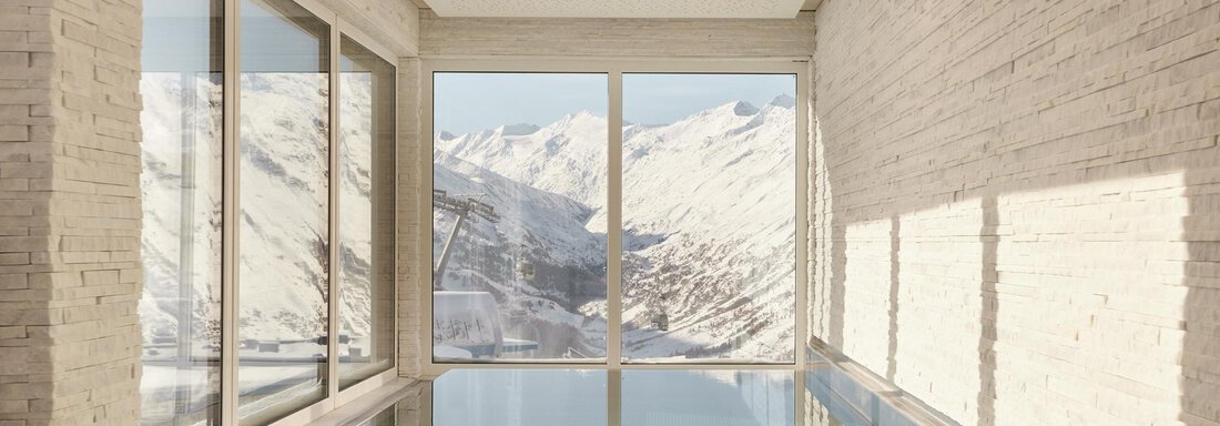 Ein moderner Raum mit einem Pool und großen Fenstern. Im Hintergrund sind schneebedeckte Berge zu sehen. - TOP Hotel Hochgurgl - Hochgurgl