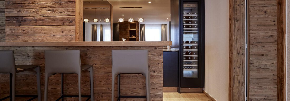 Eine moderne Küche mit Holzverkleidung und einem eleganten Bartresen. Die Atmosphäre ist einladend und hell mit warmem Licht. - TOP Hotel Hochgurgl - Hochgurgl